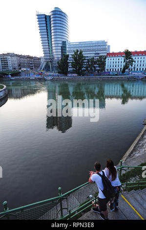 A couple enjoying the view of Uniqa tower at sunset, Donaukanal, Vienna, Austria Stock Photo