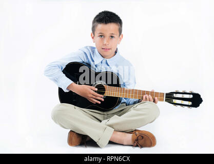 Handsome brunette boy playing guitar on white isolated background. Stock Photo