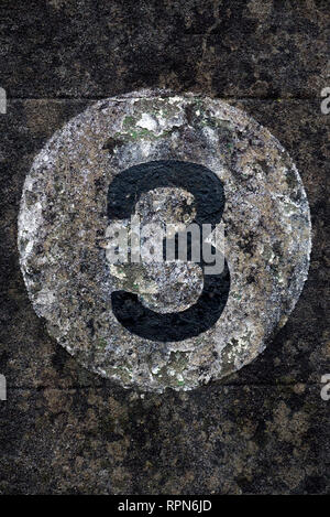 A Number Three Door Number Painted In Black Within A White Painted Circle On A Grubby Stone Wall Stock Photo