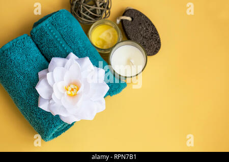 Spa still life top view with water lily flower, towel and candle on yellow background, spa and wellness setting Stock Photo
