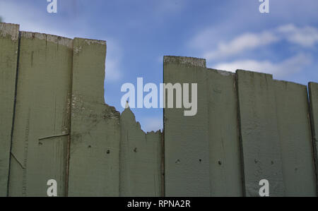 Close up view of broken wooden fence with blue sky background Stock Photo