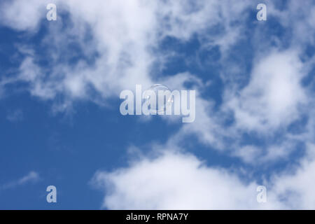 A single bubble floats against a cloudy blue sky Stock Photo