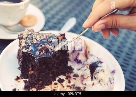brownie with icecream. sweet and dessert. female hand with a spoon separates a piece of cake. Stock photo Stock Photo
