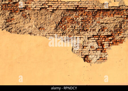 crumbling old plaster on a brick wall red orange background Stock Photo
