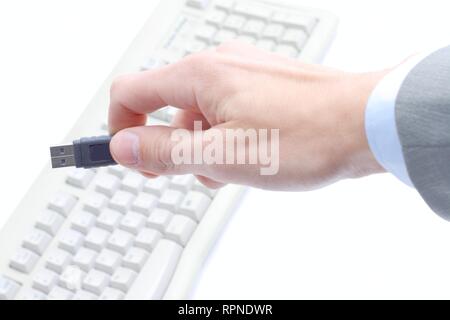close-up businessman holding a flash drive over a computer keyboard Stock Photo