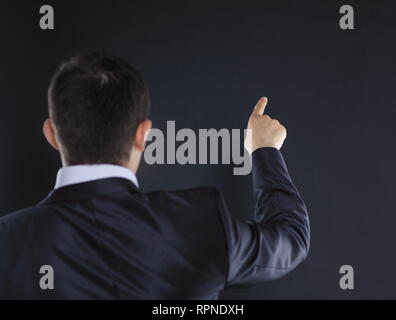 rear view.businessman pointing at copy space.isolated on black  Stock Photo