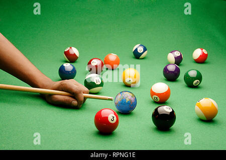 A SET OF SNOOKER/POOL BALLS  WITH A MAN ABOUT TO HIT A GLOBE OF THE WORLD, COMPOSITE IMAGE Stock Photo