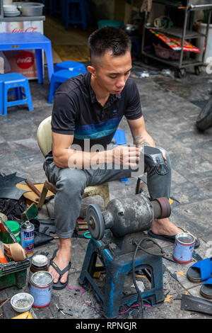 Young man repairing shoes from a street site in Hanoi old quarter, Hanoi, Vietnam, Asia Stock Photo