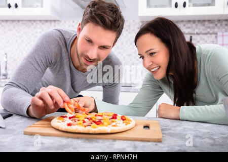 Portrait Of Happy Couple Preparing Pizza In Kitchen Stock Photo
