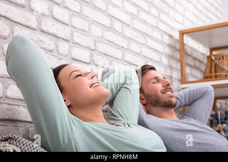 Happy Young Couple Relaxing On Sofa At Home Stock Photo