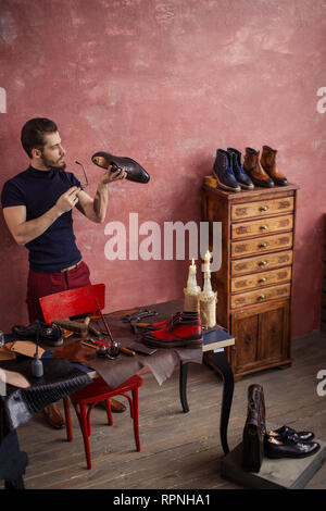 clever shoemaker examining the damaged heel ogf footwear, full length photo. copy space Stock Photo