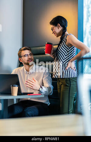 Cheerful bearded programmer talking to his colleague Stock Photo