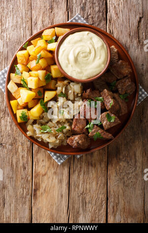Swedish Beef Rydberg with fried onions and crisp potatoes with mustard sauce close-up on a plate on the table. Vertical top view from above Stock Photo