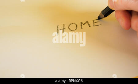 A man's hand writes the words Home with a black pencil on a white background, footage ideal for themes such as home and immigration Stock Photo