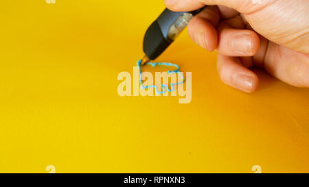 hand of a man draws with a 3d printer pen the bitcoin symbol on yellow background, footage ideal for topics such as innovation, technology and houses Stock Photo