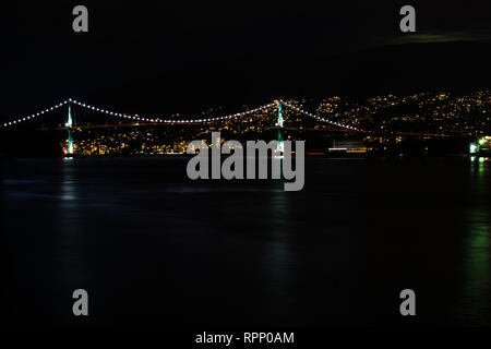 The lights of the Lions Gate Bridge in Vancouver glow like a string of pearls between Stanley Park and North Vancouver, BC. Stock Photo