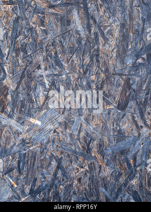 OSB boards are made of brown wood chips sanded into a wooden background. Top view of OSB wood veneer background, tight, seamless surfaces. Stock Photo
