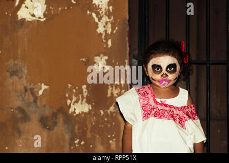 Mexican little girl with pink dummie with traditionnal day of the dead make up during annual celebration in Merida, Yucatan, Mexico - 31.10.2018 Stock Photo