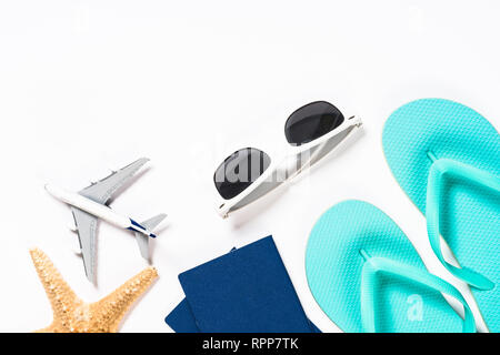 Blue flip flops, sunglasses, passport, plane and starfish on white background. Stock Photo