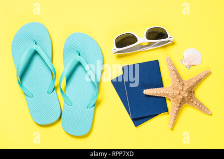 Blue flip flops, sunglasses, passport and starfish on yellow background. Stock Photo