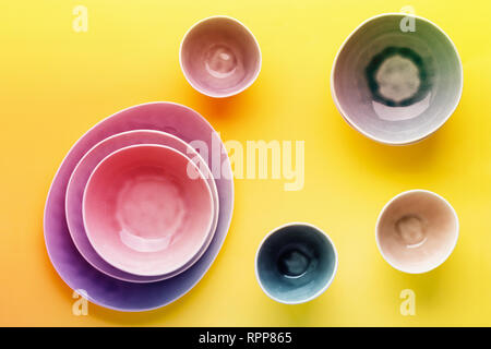 Beautiful blue, grey, beige dinnerware, plates bowls on yellow background table, top view, vibrant toned, neon colors, selective focus Stock Photo