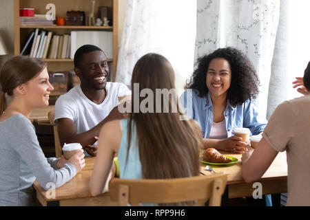 Happy multiracial friends laughing at joke, drinking coffee in cafe Stock Photo