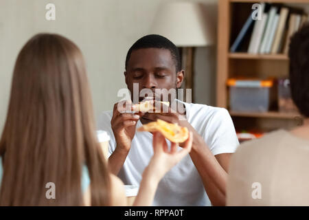 Happy African American man enjoying pizza with friends Stock Photo