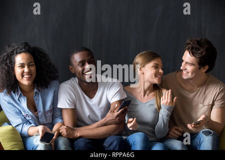 Laughing multiracial friends having fun together, holding phones Stock Photo