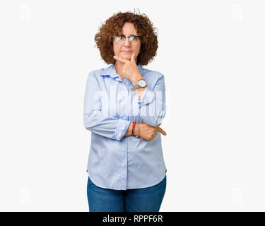 Beautiful middle ager senior businees woman wearing glasses over isolated background looking confident at the camera with smile with crossed arms and  Stock Photo
