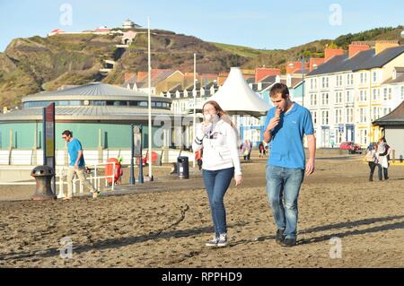 Aberystwyth Wales UK. Friday 22 Feb 2019 UK weather: Peopke enjoying the incredibly warm February sunshine in Aberystwyth on the west coast of Wales. The weather is forecast to remain fine for the next few days with the chance of record breaking temperatures in some places photo Credit: Keith Morris/Alamy Live News Stock Photo