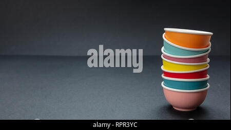 Colorful clean ceramic bowls stacked on black color background, copy space, front view Stock Photo
