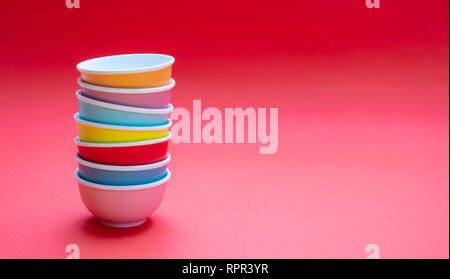 Colorful clean ceramic bowls stacked on red color background, copy space, front view Stock Photo