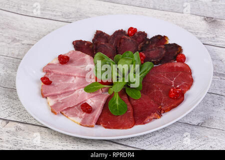 Meat plate with horse, beef and chicken sausages with salad leaves Stock Photo