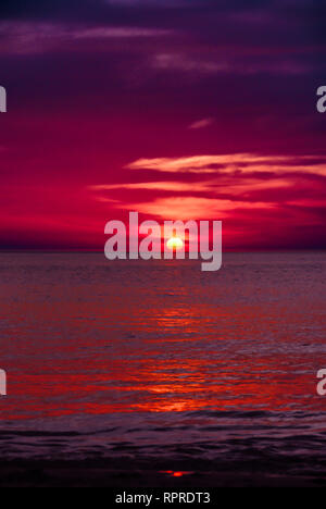 Blood red and dark purple sunset of sun sets over horizon Adaman Sea only couds and water Stock Photo