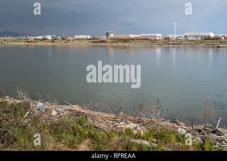 Llobregat River with industrial area in background and plastic bottles in the foreground. Natural Areas of the Llobregat Delta. Catalonia. Spain. Stock Photo