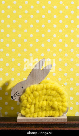 Yellow easter bunny in front of wall of points in a room. Bunny decoration and yellow wallpaper background on dots. Shadow of rabbit on the wall. Wood Stock Photo