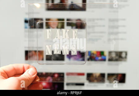Fake news text and website on the background. Fake news conception with transparent words. Blurred Images and articles on background. Stock Photo