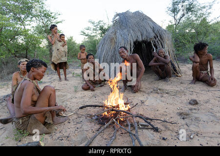 Bushmen of the San people singing and dancing traditional dances around the fire in front of the hut, Kalahari, Namibia, Africa Stock Photo