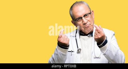 Handsome senior doctor man wearing medical coat Doing money gesture with hand, asking for salary payment, millionaire business Stock Photo