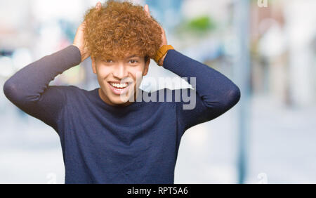 Young handsome man with afro hair Posing funny and crazy with fingers on head as bunny ears, smiling cheerful Stock Photo