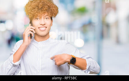 Young handsome man talking on the phone with surprise face pointing finger to himself Stock Photo