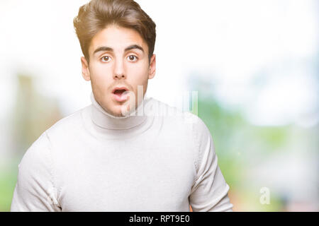 Young handsome man wearing turtleneck sweater over isolated background afraid and shocked with surprise expression, fear and excited face. Stock Photo