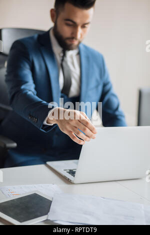 awesome office worker using the computer in the office.close up photo.blurred image. focus on laptop. hardworking employee is looking at the screen of Stock Photo