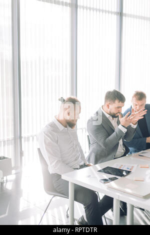 Businessman arguing with colleagues looking at him during meeting at conference room Stock Photo