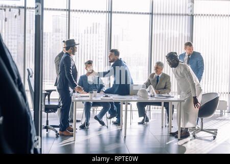 Diverse business executives discussing project sitting at conference table, multiracial partners talking about marketing plan at corporate briefing, a Stock Photo
