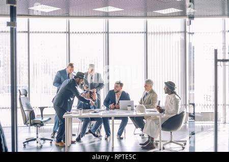 Cheeful multiracial group of businessmen having fun during meeting in office room, excited male employees laughing enjoying funny jokes at work break. Stock Photo