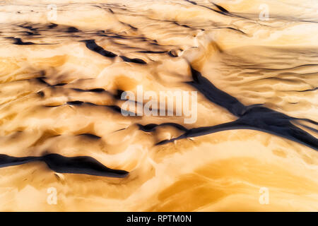 Yellow hardened surface of sand dunes in arid deserted area of Stockton beach - aerial overhead view on eroded wind formed abstract shapes of ground. Stock Photo