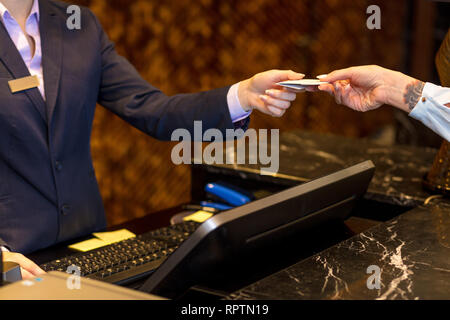 Easy transaction, woman paying with a credit card at hotel reception, close up. Stock Photo