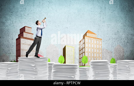 Businessman playing fife while standing on pile of documents with drawn cityscape on background. Mixed media. Stock Photo