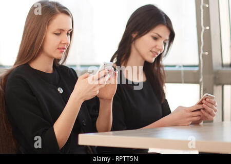 employees using their smartphones sitting at a table in a cafe Stock Photo